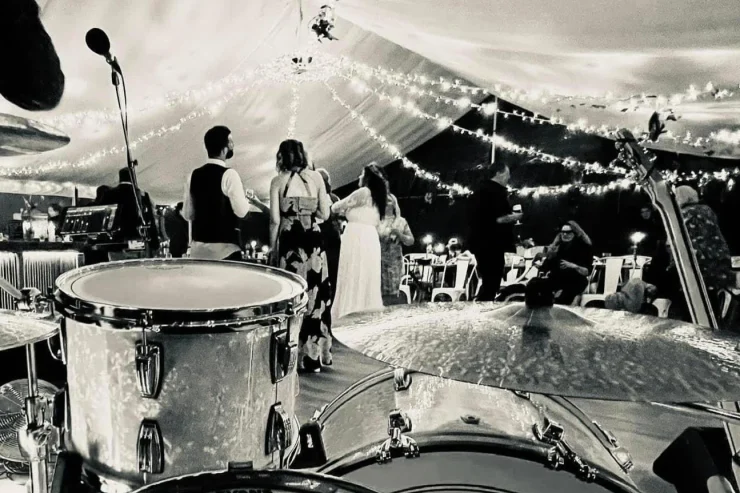 black and white photo of a drum kit and wedding guests dancing