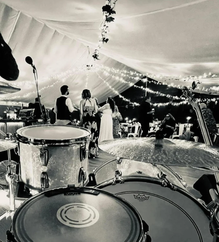 black and white photo of a drum kit and wedding guests dancing