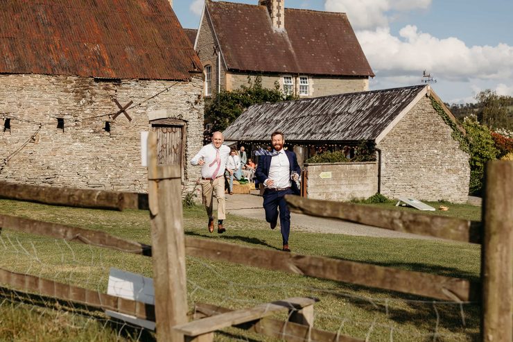 Two men running towards the camera on the grounds. Both smiling and happy