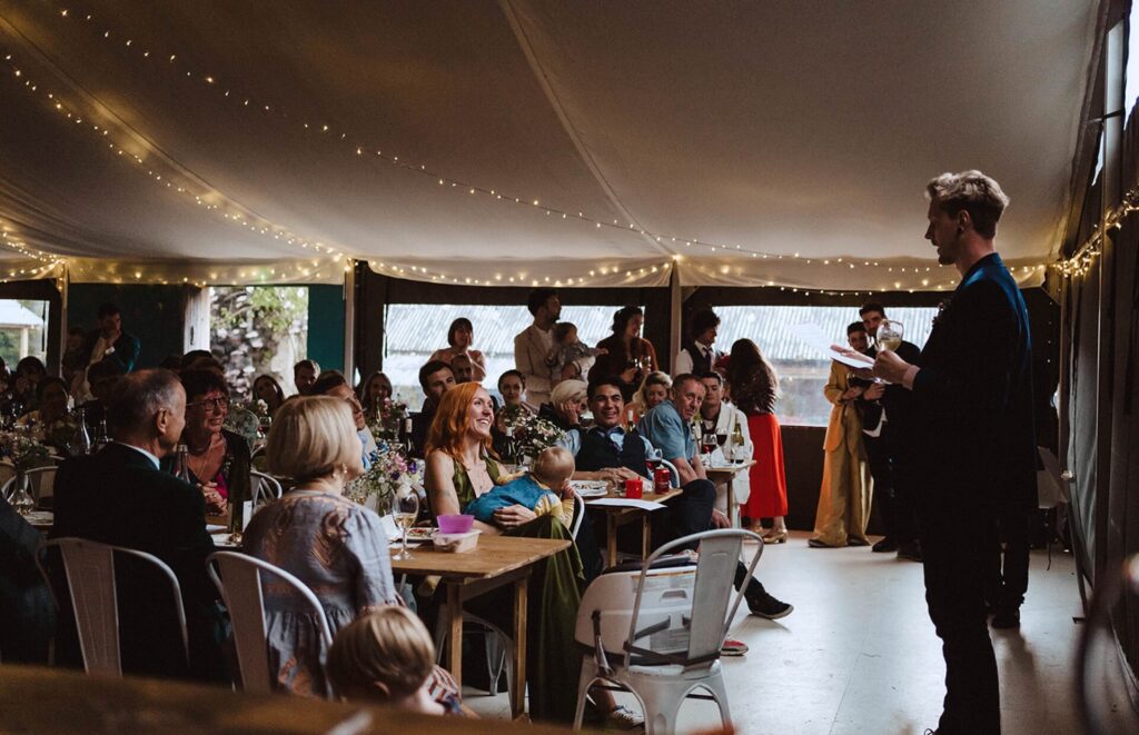 Best man speech at a wedding. A man stood talking to a room full of the reception guests