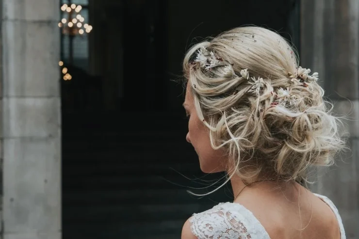 A lady on her wedding day with her blonde hair in a low messy bun with flowers in her hair