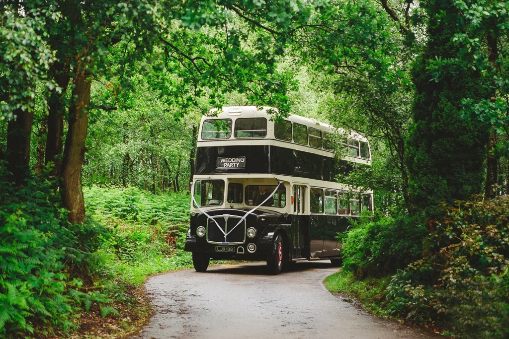 An old double decker bus driving down a country lane