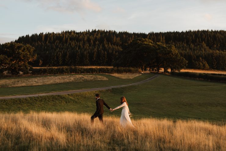 wedding couple walking through fields at twilight